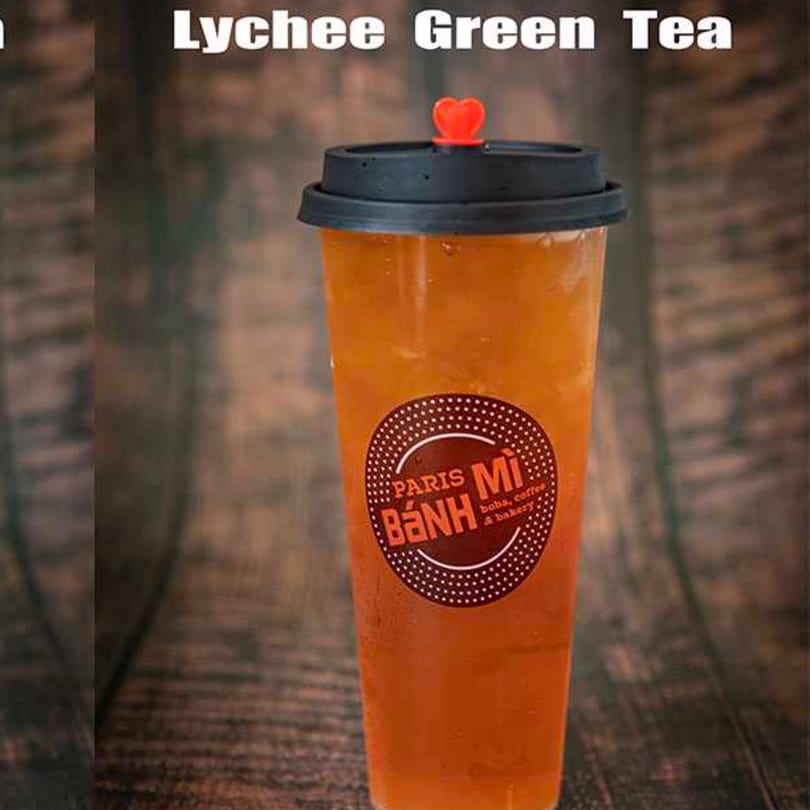 A tall plastic cup of Lychee Green Tea from Paris Banh Mi, with a red heart on the lid.