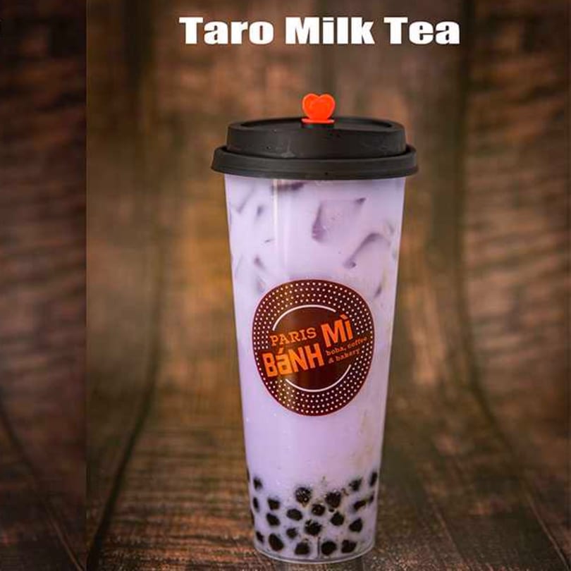 A Paris Banh Mi Taro Milk Tea with boba pearls, ice, and a heart-shaped stopper.