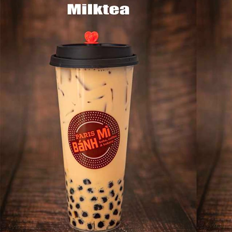 Paris Banh Mi milk tea with boba and ice in a clear cup with a red heart stopper.