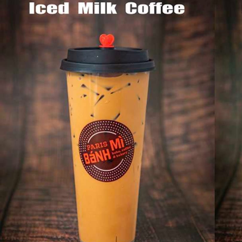 Iced milk coffee from Paris Banh Mi Augusta LLC, with a heart-shaped stopper on a wooden background.