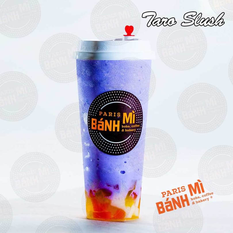 A Paris Banh Mi Taro Slush drink, purple with colorful fruit at the bottom, on a white background.