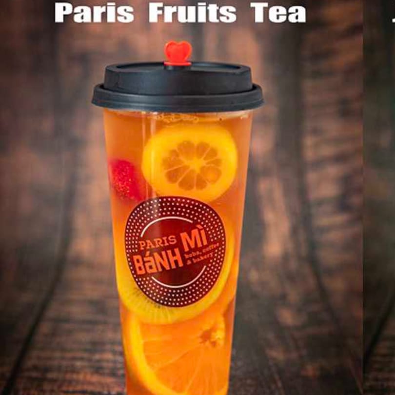 Paris Fruits Tea with orange and strawberry slices, featuring the Paris Banh Mi logo on a wooden background.