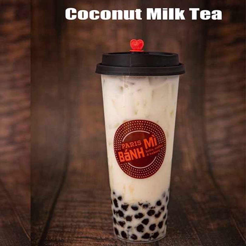 Coconut Milk Tea with boba from Paris Banh Mi, served in a clear cup with a red heart stopper.