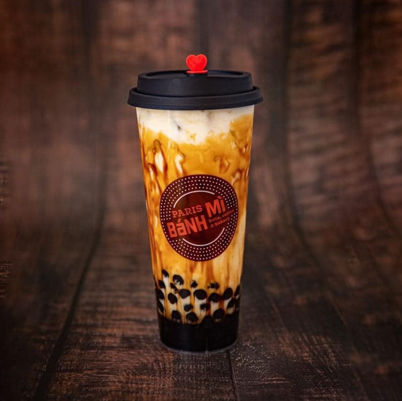 Paris Banh Mi boba tea with dark pearls, creamy white, and caramel swirls, topped with a red heart.