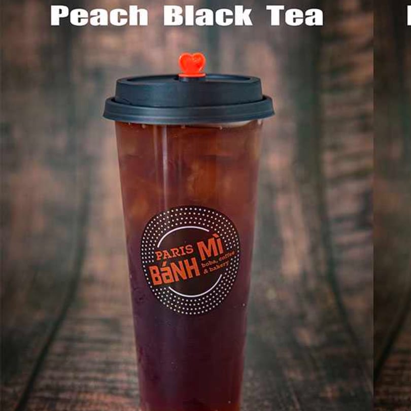 Peach Black Tea from Paris Banh Mi Augusta, a Vietnamese restaurant, in a clear cup with a black lid.