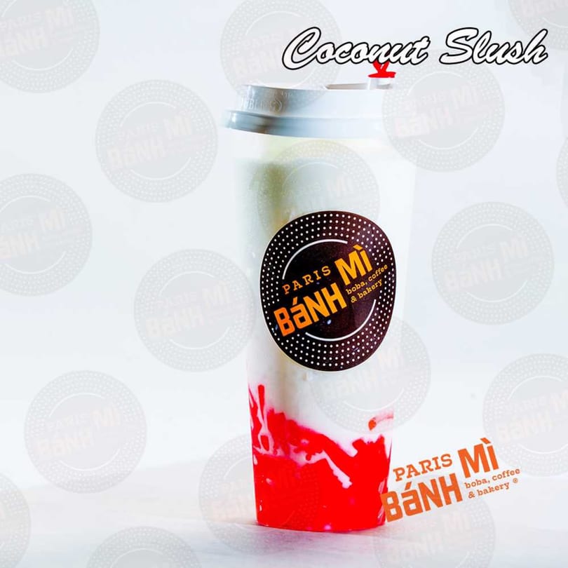 A Paris Banh Mi coconut slush with red syrup, a white lid, and the brand logo.