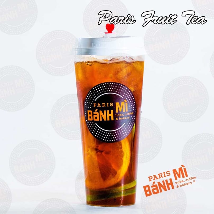 Paris Banh Mi's fruit tea with orange and lime slices, ice, and a branded label.