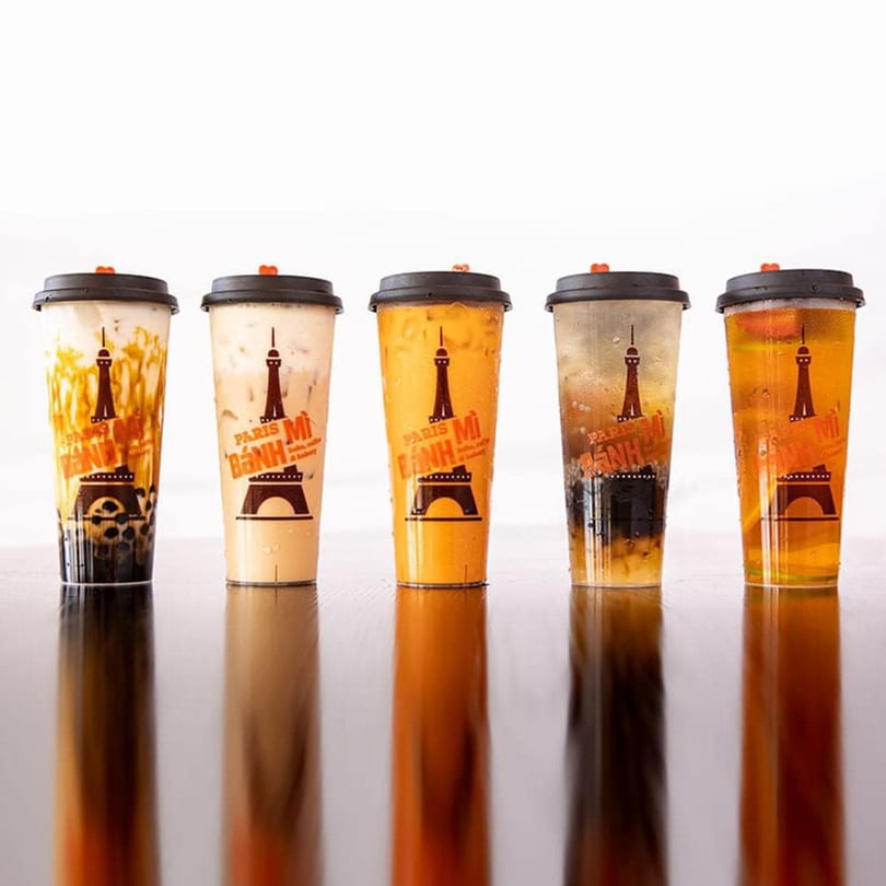 Five Paris Banh Mi bubble tea drinks in clear cups with black lids on a reflective surface.