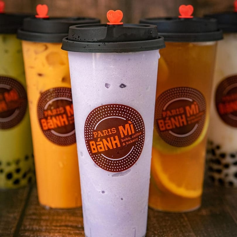 Assortment of Paris Banh Mi boba drinks in various colors, including purple, orange, and green.